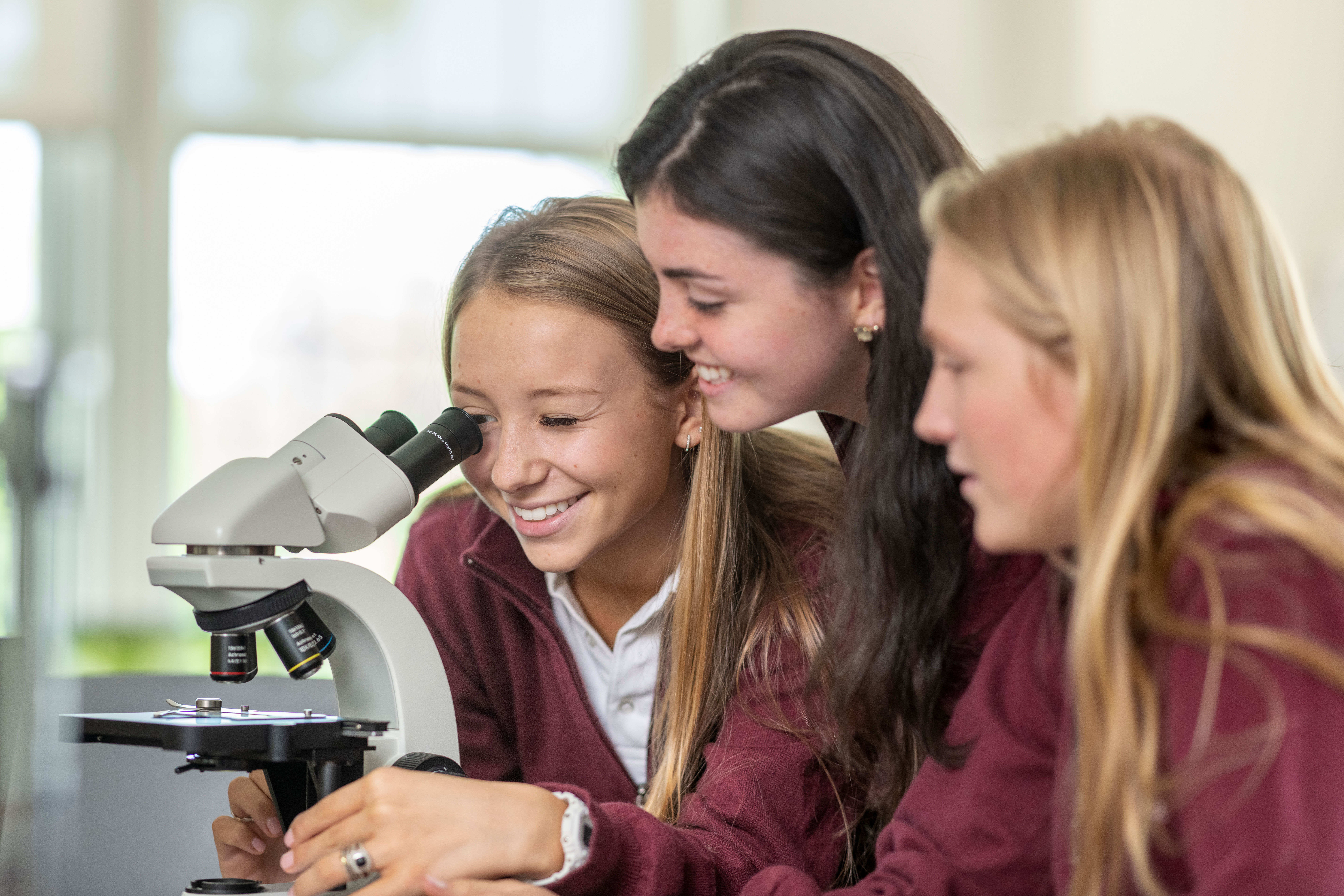 Upper School students looking into a microscope at Oak Knoll