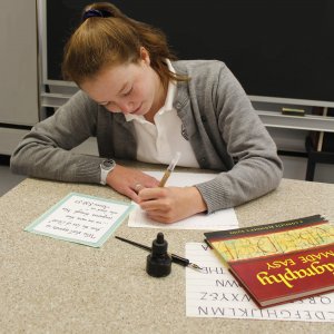 An Oak Knoll student practices calligraphy during Scribes club