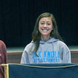 Three students standing next to school podium.