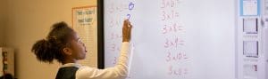 Girl completes math problem on smartboard.
