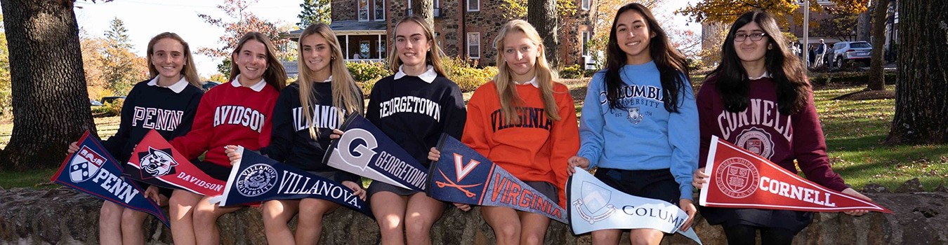 College bound athletes pose with banners with their respective college names on them.