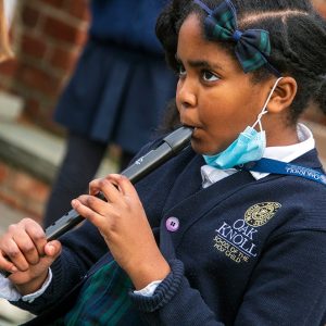 Student plays recorder during class outside.