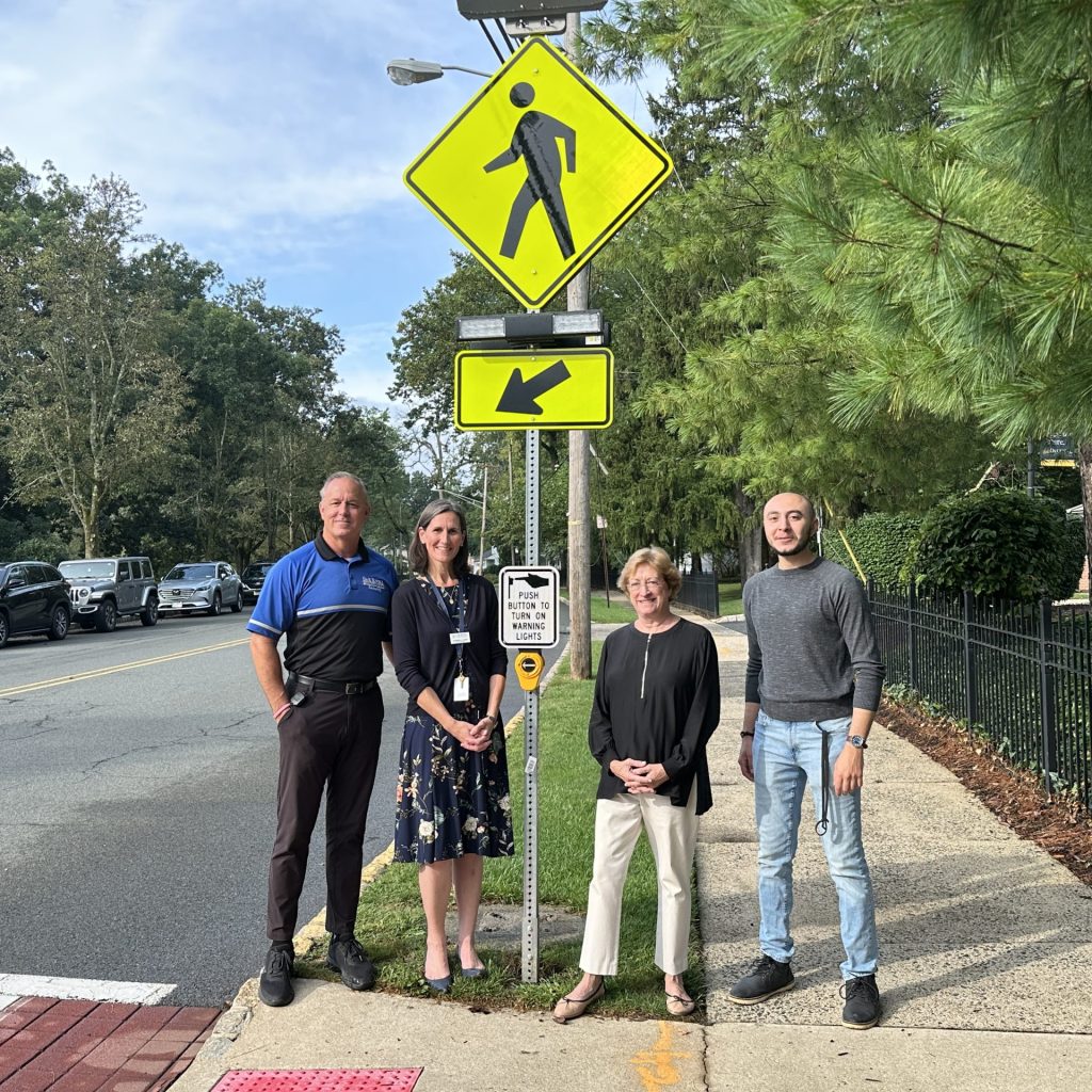 Oak Knoll School and City of Summit officials pose for a phone in front of a pedestrian safety signal.